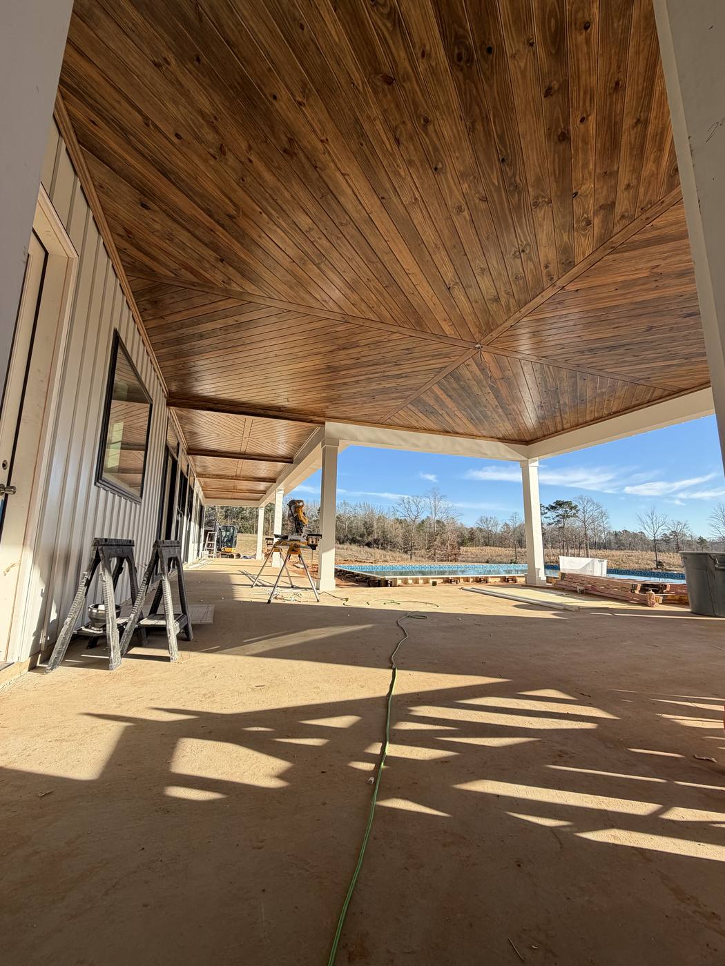 Covered patio with wood plank ceiling and pool view