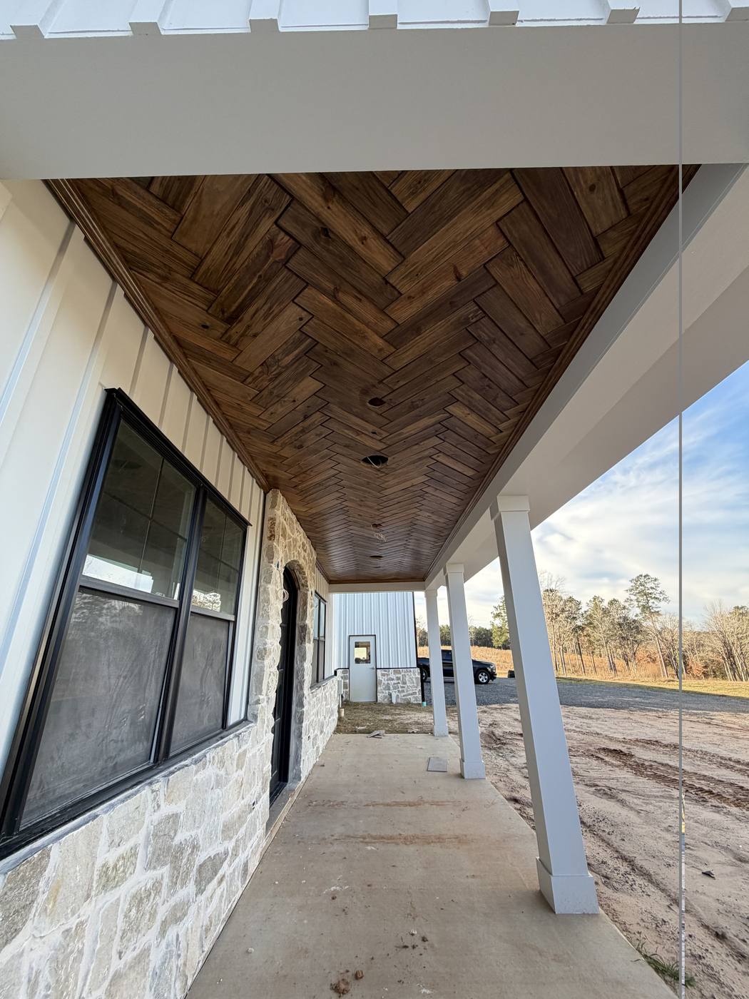 Herringbone wood plank porch ceiling with stone column